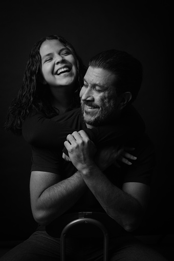 Young couple in love hug each other on the black background.