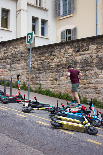 Lyon, France: A man jogs past electric scooters strewn on a street in the Fourviere district near the cathedral.