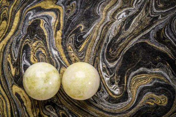 a pair of green marble Chinese medicine balls against black and golden marbled paper
