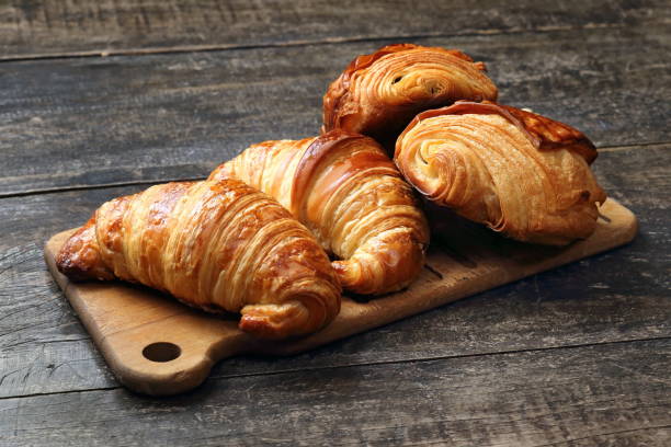 croissant e pão de chocolate na tábua de madeira - butter bread breakfast table - fotografias e filmes do acervo