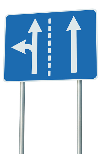 Appropriate traffic lanes at crossroads junction, left turn exit ahead, isolated blue road sign, white arrows, frame, background, EU European roadside signage, alternative route choice metaphor, grey pole posts, large detailed vertical closeup