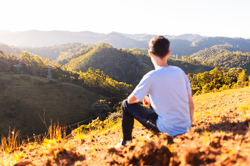 Defocused man contemplating view with camera focus on landscape in background.
