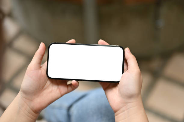 istock A female holding her smartphone in a horizontal position while sitting outdoors 1494439587
