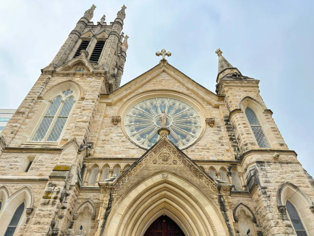 Looking up at the front towers and a statue of the friar in front of the Saint Fidelis Catholic Church in Victoria, Kansas. It was the largest church west of the Mississippi River when it was completed in 1911.  It is built from limestone blocks, a mineral easily accessible in that part of the world, and each block weighed between 50 and 100 pounds.  The structure can be seen rising out of the flat plains of Kansas, giving meaning to its more common name, the Cathedral of the Plains.