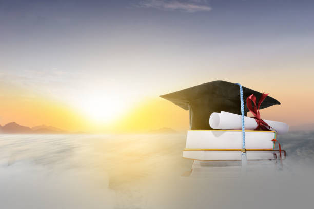 The pile of books and graduation scroll with graduation caps stock photo