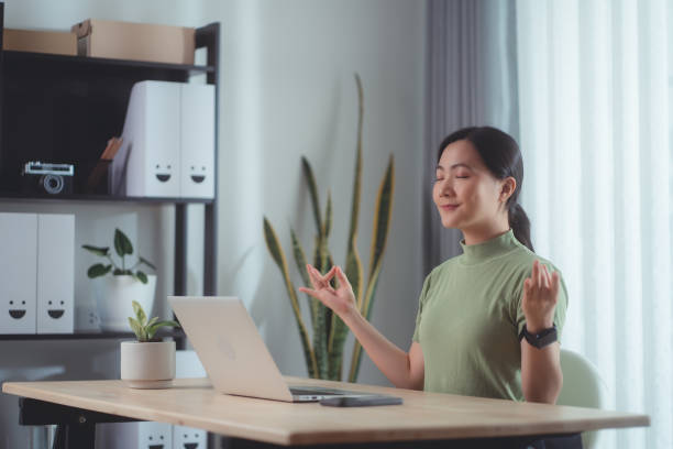 Asian woman calms down taking a break with meditating holding her hands in yoga gesture sitting at home office. Asian woman calms down taking a break with meditating holding her hands in yoga gesture sitting at home office. Happy woman working from home. meditation room office stock pictures, royalty-free photos & images