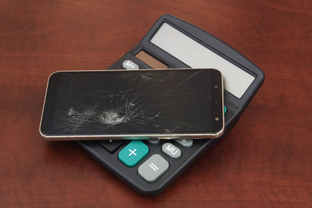 istock Broken smartphone on calculator on wooden table. 1494460689