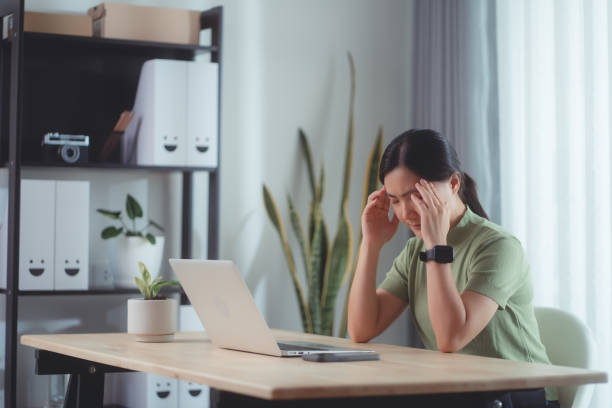 istock Asian woman suffering from headache sitting at home office. 1494461549