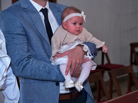 Midsection of father holding his baby girl in a church ready for christening