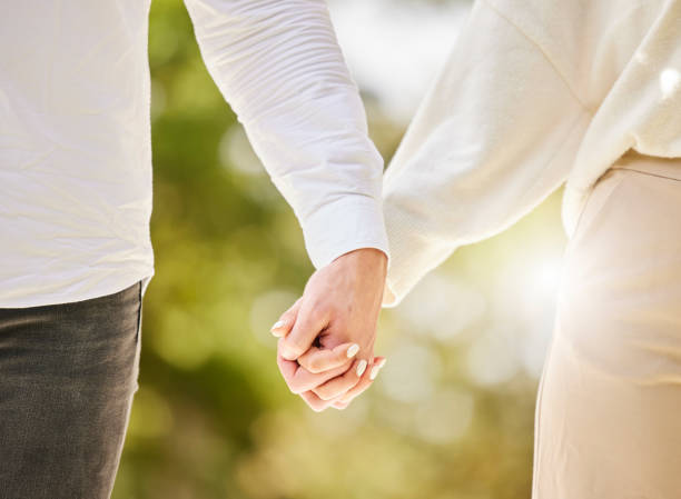 istock Couple holding hands in park for love, care and save the date marriage commitment together. Closeup hand of man, woman and walking in nature, garden and sunshine for relax, trust and support partner 1494467702