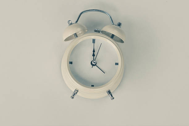 istock White alarm clock with five minutes to twelve o'clock, retro clock. 1494467873