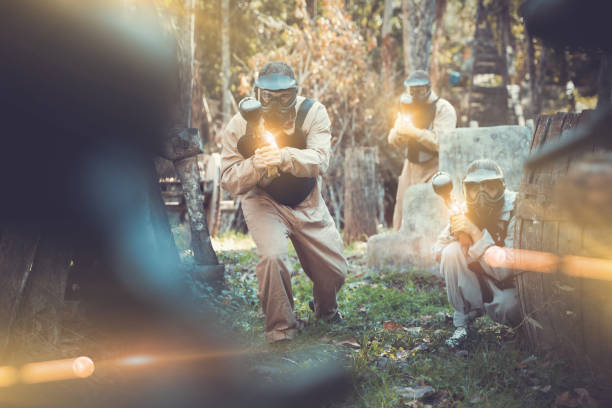 Teams playing paintball outdoors Teams of friends facing on battlefield in outdoor paintball arena, image with glowing and blur effects paintball photography stock pictures, royalty-free photos & images