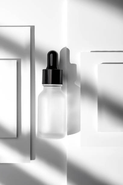 istock matte glass cosmetic dropper bottle with blank label on white layered background with gobo shadows. Trendy beauty product design, branding. Mockup cosmetics 1494478644