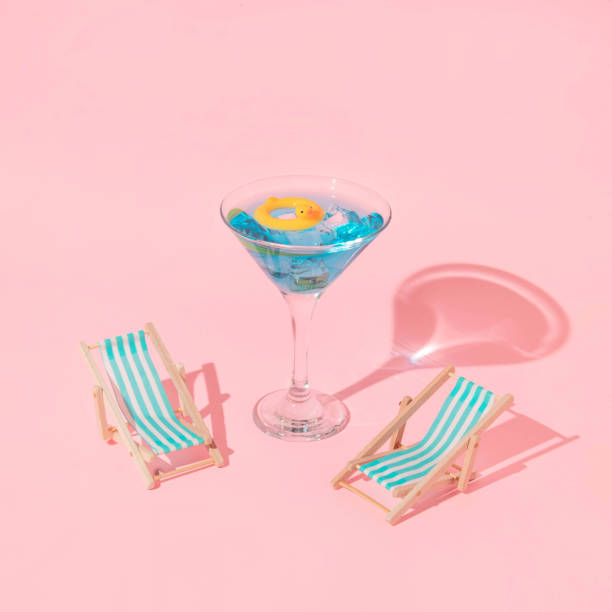 aménagement créatif d’été avec verre de martini avec anneau de bain de canard et chaises de plage sur fond rose. idée esthétique rétro des années 80 ou 90. idée de cocktail d’été minimal. - image created 1990s photos et images de collection