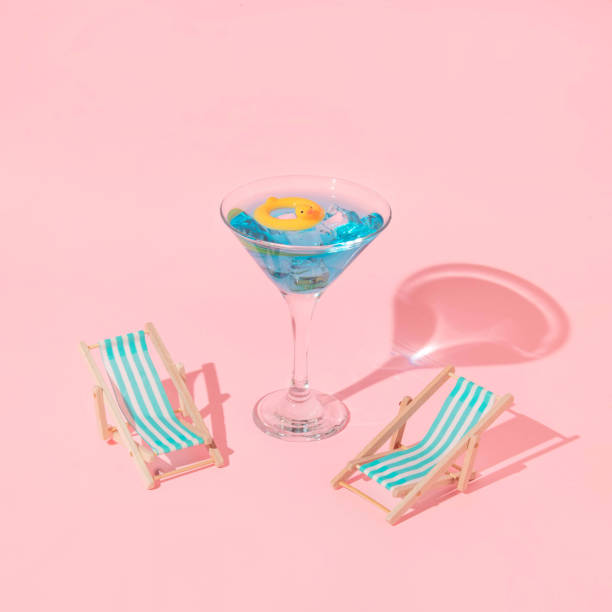ピンクの背景にマティーニのコクテールグラスとアヒルの水泳リングとビーチチェアを持つ夏のクリエイティブレイアウト。80年代または90年代のレトロな美的アイデア。最小限の夏のコクテ - ice float ストックフォトと画像