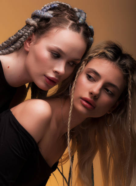 istock Two girlfriend hugging each other, feeling love, posing in black bodysuit with long hair, perfect lips and skin, looking in camera on warm orange background. 1494479356