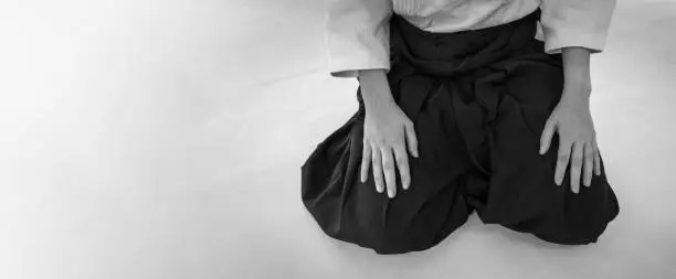 Woman practicing aikido martial art in a dojo background. Seiza position.