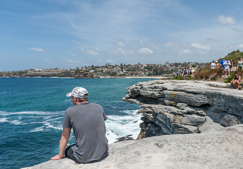 Sydney, Australia - November 7, 2014: Unidentified Person Sitting on the edge of rock, close to ocean in Sydney, Australia. Mackenzies Point.