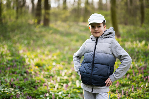 Portrait of boy in cap on sunny forest. Outdoor spring leisure concept.