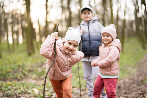A woman is hiking in the woods with her young son. She is crouching on the ground and has her son in her arms. It is springtime.