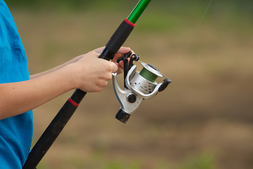 Fishing rod with a reel in the hands of a child close-up. High quality photo