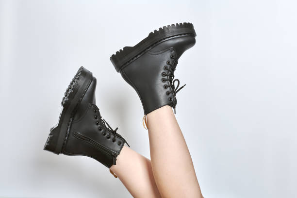 istock Woman legs in black combat boots on high heel platform with lug soles upside down, white background 1494491182