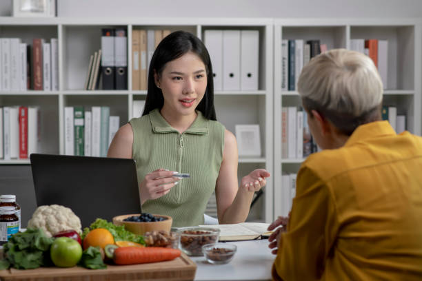 Nutritionist with woman client Nutritionist with woman client talking about meal plan and healthy products during a medical consultation in the office nutritionist stock pictures, royalty-free photos & images