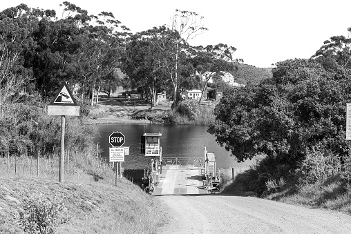 Malagas, South Africa - Sep 24, 2022: The ferry over the Breede River at Malagas in the Western Cape Province. Road signs are visible. Monochrome