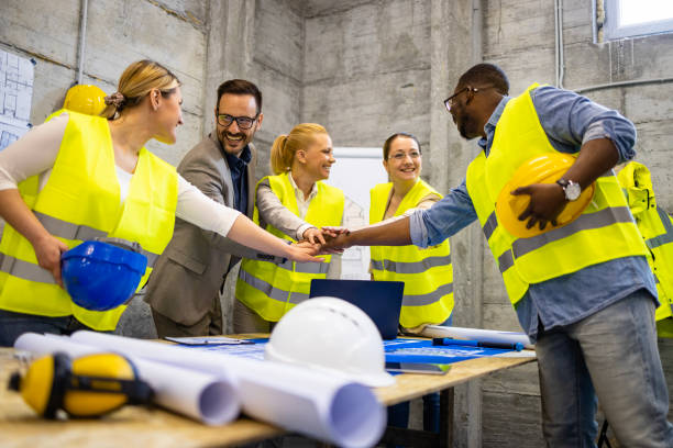 istock Team of construction engineers holding hands together at build site. 1494498305