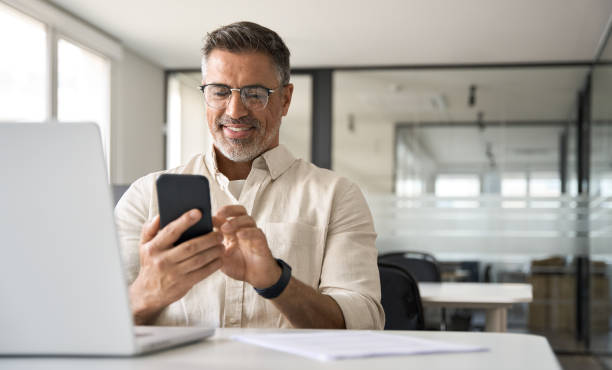 istock Middle aged Hispanic manager ceo businessman using cell phone mobile app, laptop 1494498490