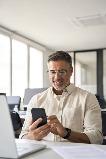 istock Vertical portrait of middle aged Hispanic business using cell phone mobile app. 1494498509