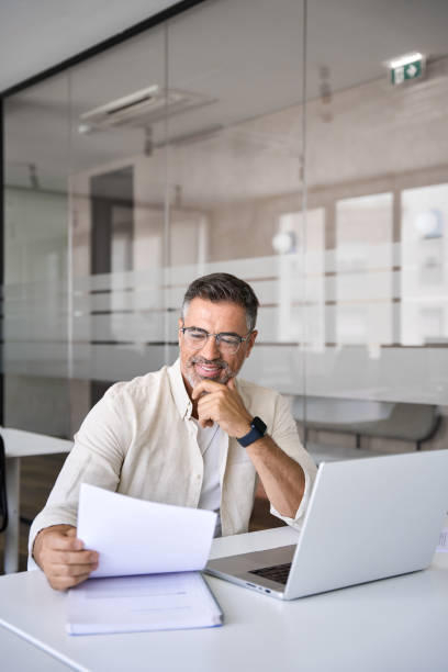 Vertical portrait of Hispanic businessman working in office and doing paperwork. stock photo