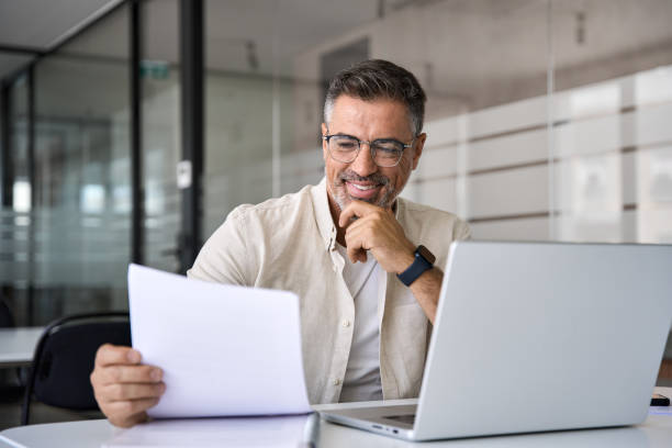 istock Smiling Latin businessman accountant analyst holding documents, work at laptop 1494498529
