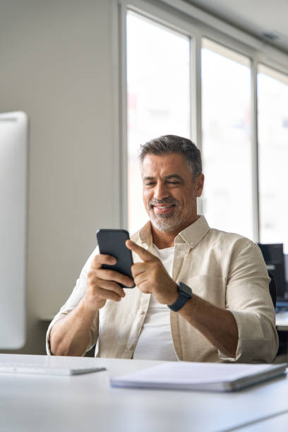 istock Vertical portrait of middle aged Hispanic business using cell phone mobile app. 1494498569