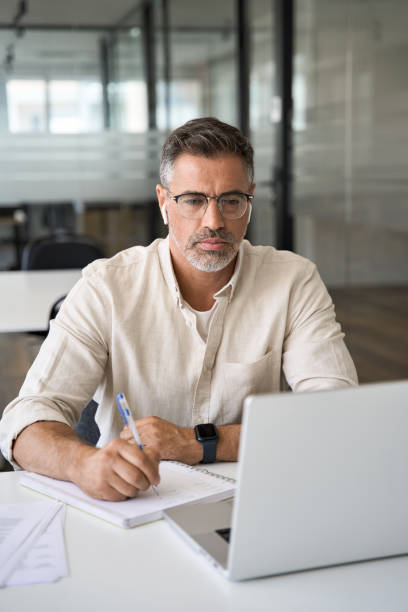 Vertical portrait of middle-age Hispanic man using laptop for business studying stock photo