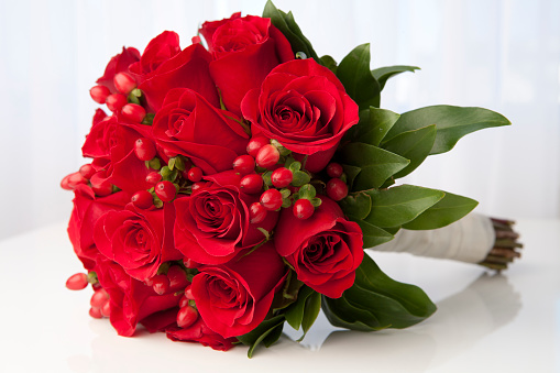 A bouquet of red roses with drops of water on a mirror table with a beautiful reflection, decorative hearts.Floral background for Valentine's Day.Festive background for wedding,mother's day,birthday