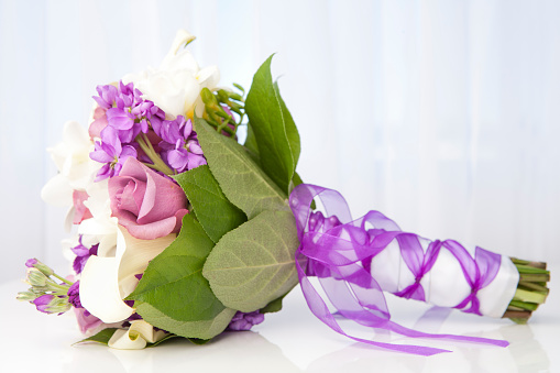 Variation of purple and white wedding bouquet on table.