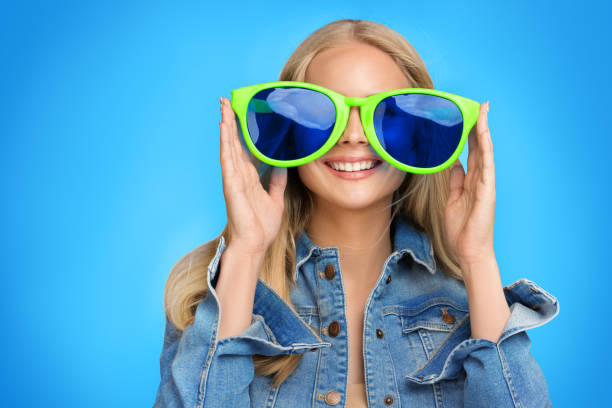 ragazza adolescente felice in occhiali da vista di partito che si divertono. giovane donna sorridente in grandi occhiali che guarda blue screen. ritratto di allegra adolescente femminile che gioca gioco - occhiali giocattolo foto e immagini stock