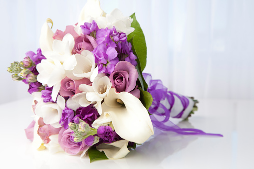 Variation of purple and white wedding bouquet on table.