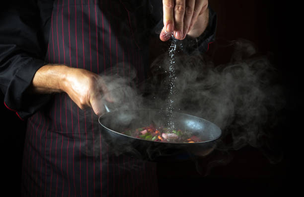 istock Experienced chef adds salt to a steaming hot pan. Molecular cuisine menu idea for a hotel with advertising space 1494500967