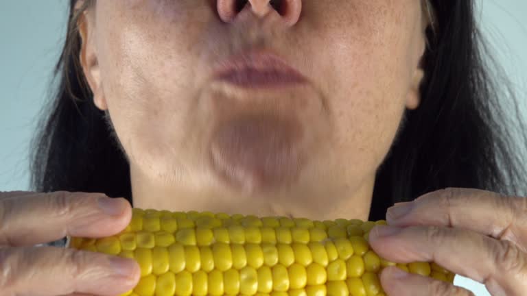 mouth of woman eating an ear of corn closeup