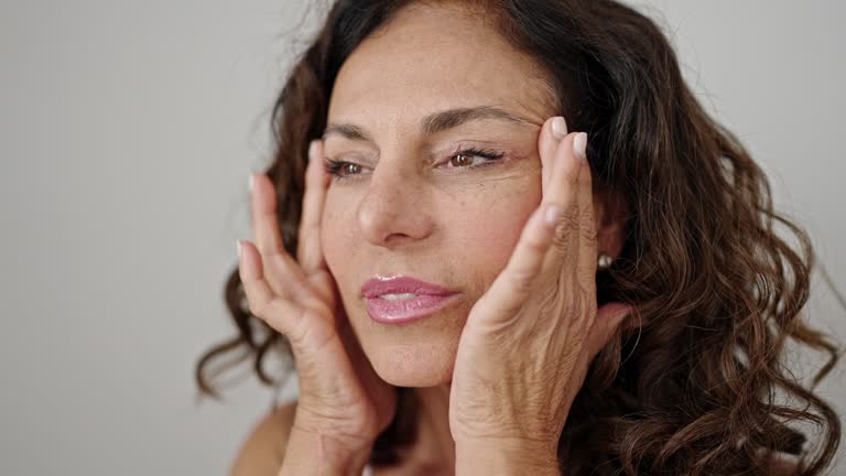 Middle age hispanic woman smiling confident applying skin treatment over isolated white background