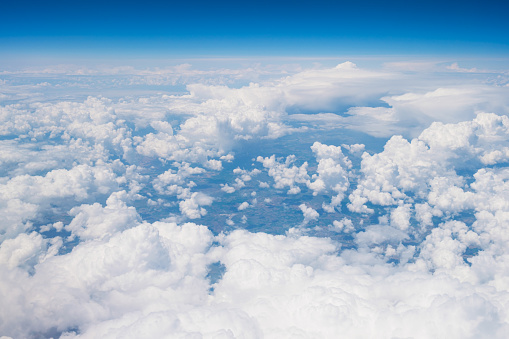 Abstract blue sky background with Cumulus clouds. Beautiful daytime sky with clouds. View from the airplane window