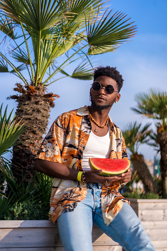 Black ethnic man enjoy summer vacation on the beach with a watermelon