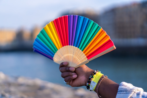 Colorful rainbow fan during gay pride, LGBT collective fan by the sea