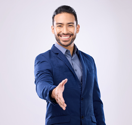 Business man, handshake and studio portrait for welcome, smile or agreement for partnership by background. Asian young entrepreneur, shaking hands or excited face for opportunity, greeting or respect