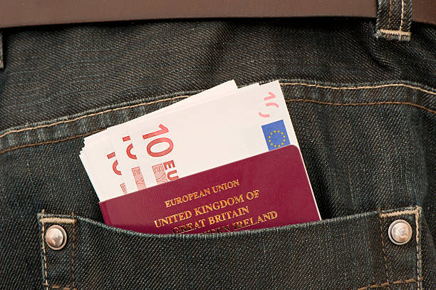 Travel Close up of European Union currency and a British passport in the back pocket of some denim jeans. jeans denim passport pocket stock pictures, royalty-free photos & images