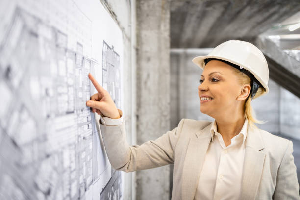 istock Female blonde architect looking at construction blueprint and smiling. 1494516891