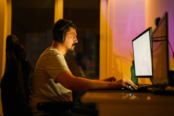 istock male sitting at the table at night playing computer game and broadcasting live. 1494521140
