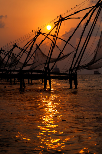 Sunset over Chinese Fishing nets and boat in Cochin (Kochi), Kerala, India.